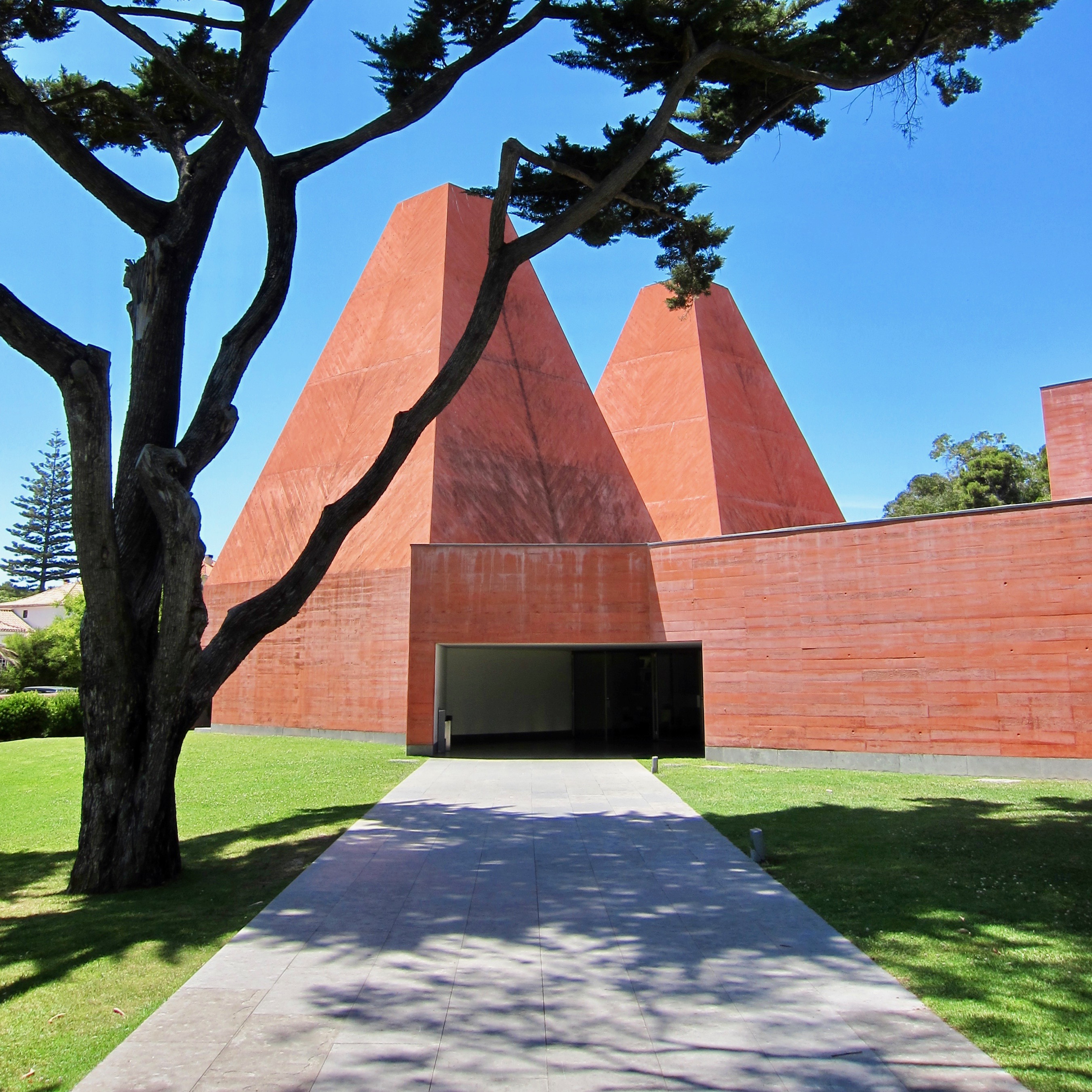 a set of reddish buildings beyond a large tree