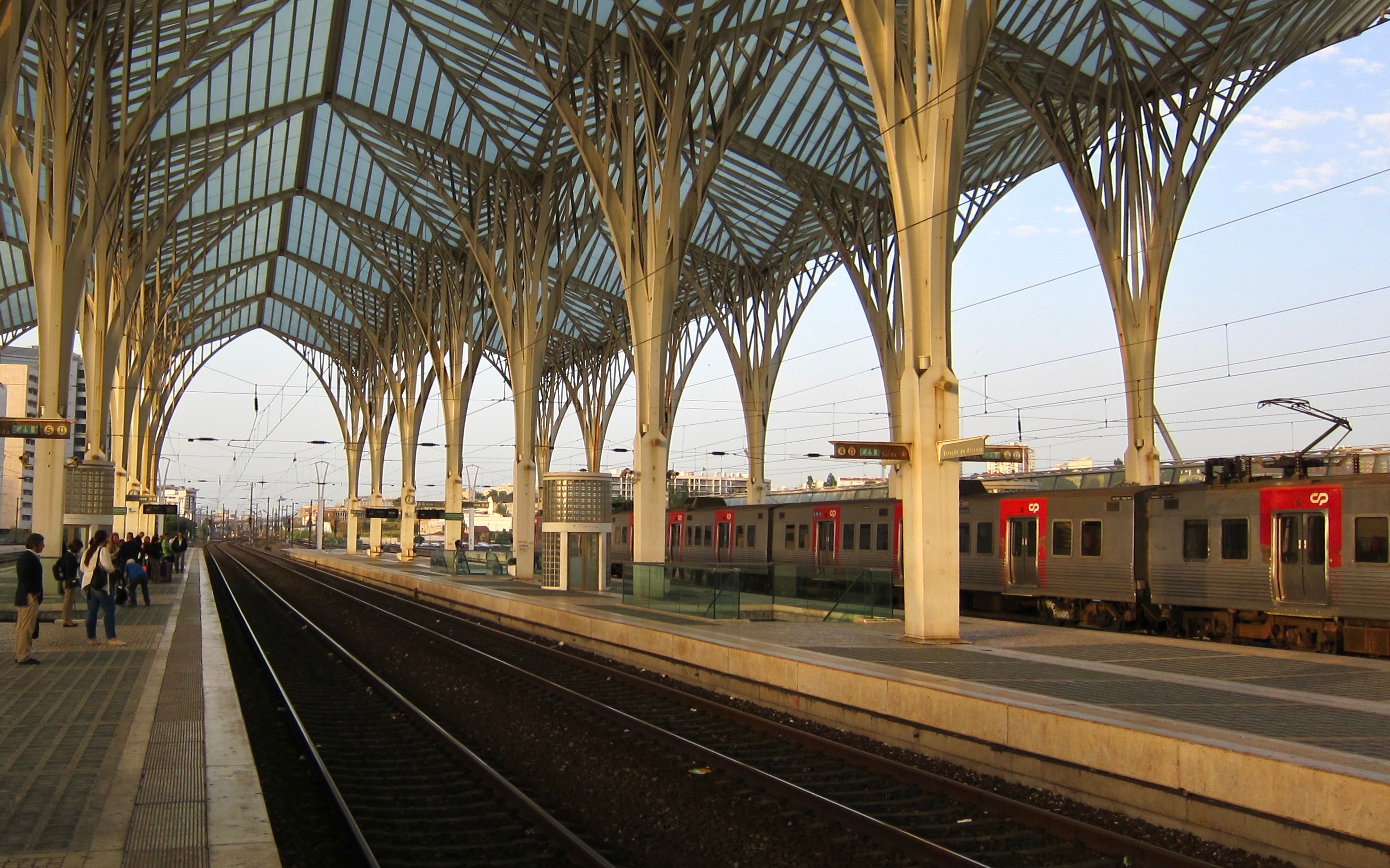 under the archways of a modern thrain station. A train sits in the other track.